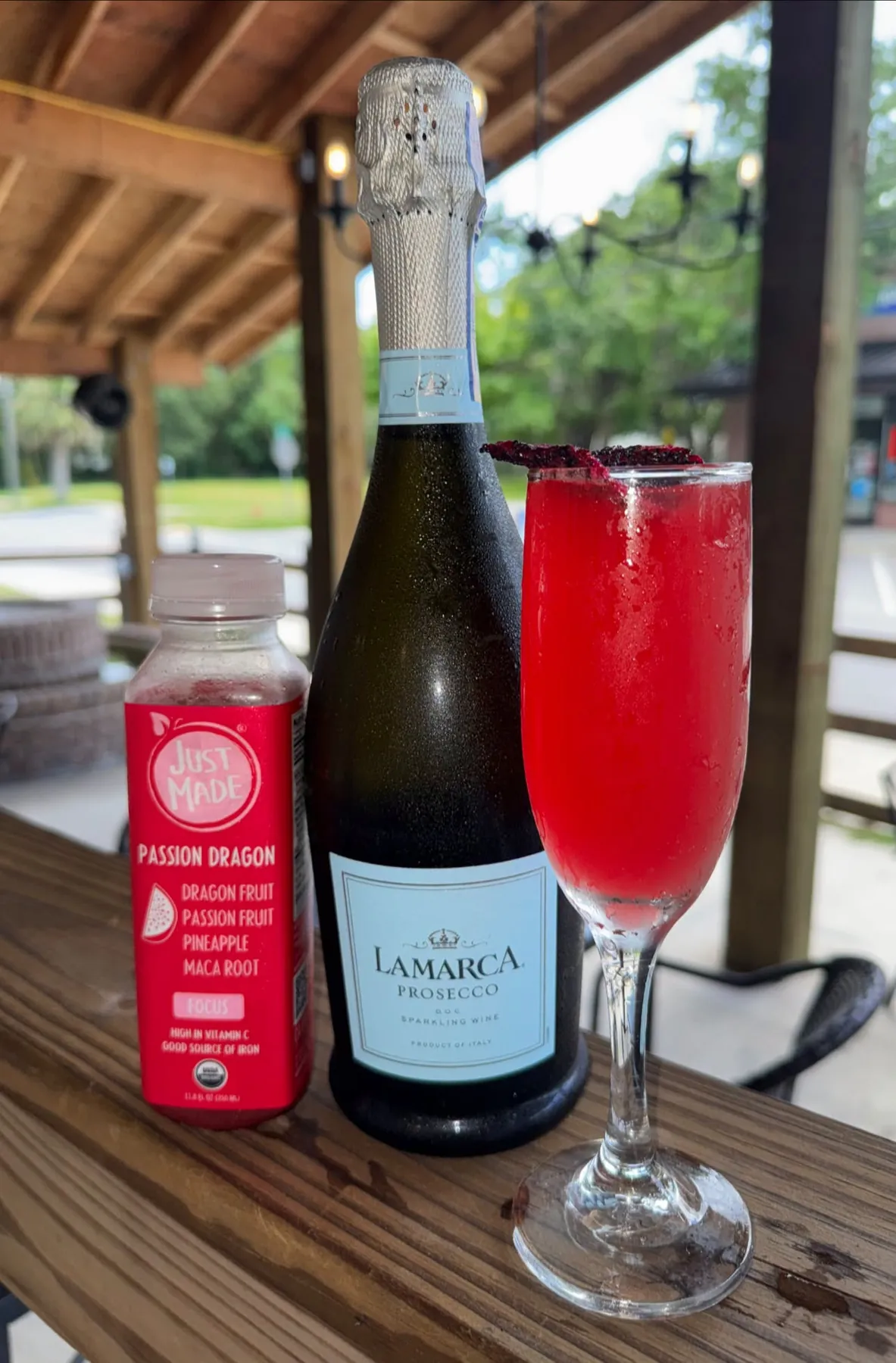 Sparkling wine bottle and a red mimosa on the patio